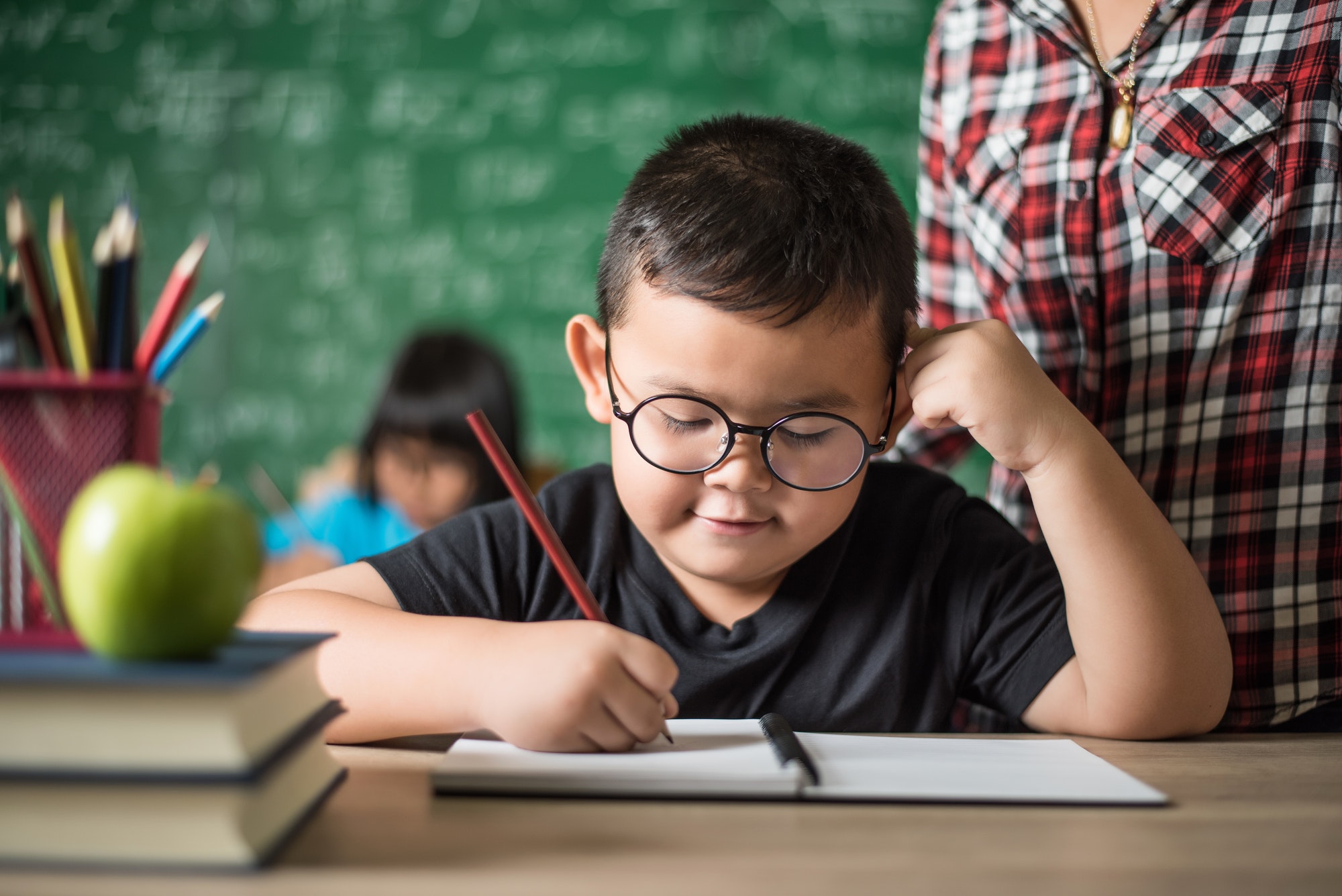 kid write a book in the classroom.